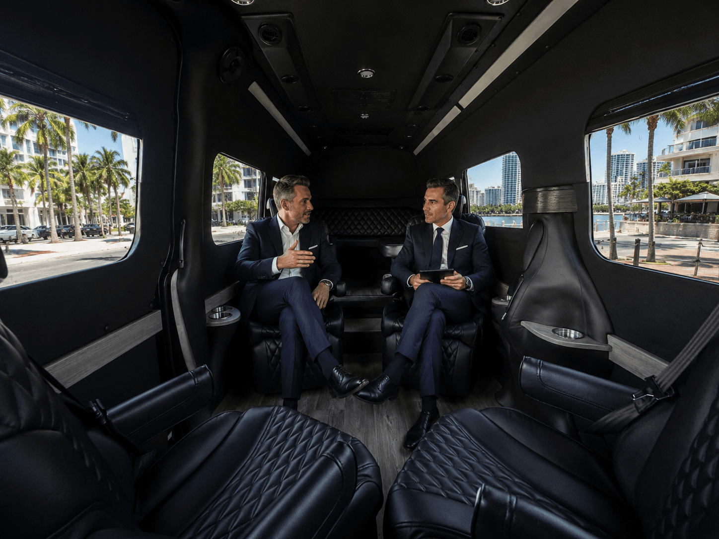 Two executives in conversation inside a Miami Bus Company Sprinter VIP interior